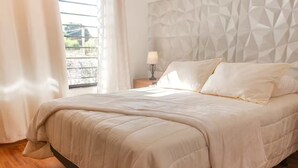 A neatly made bed with a quilted cover, a bedside lamp, and a geometric-patterned headboard. - Casa con la mejor ubicación a minutos de Xetulul (Santa Cruz Muluá)