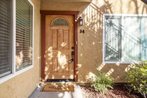 A wooden front door with a glass panel, a mailbox, and a number '34' on the wall.