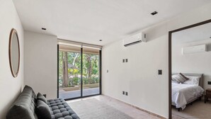 Un dormitorio moderno con una cama grande, un sofá y un ventanal corredera que da a un balcón.