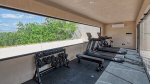 Un gimnasio moderno con cintas de correr, mancuernas y una bicicleta estática.