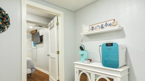 Een gang met een witte deur, een witte console en een blauw apparaat, en een plank met decoratieve objecten.