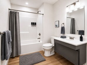 Une salle de bain moderne équipée d’une baignoire, de toilettes et d’un meuble-lavabo.
