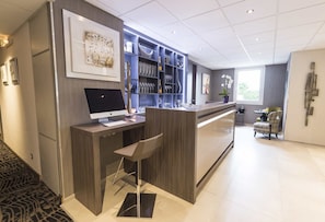 Un hall d’hôtel moderne comprenant un comptoir d’accueil, un ordinateur et un espace bar.