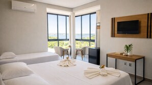 A hotel room with two beds, a desk, a TV, and a balcony with a view. - Pousada Casa Decore (Capitólio)