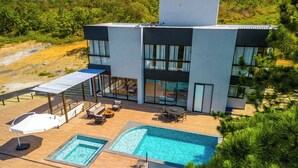 A modern two-story building with a swimming pool, outdoor seating, and a covered patio area. - Pousada Casa Decore (Capitólio)