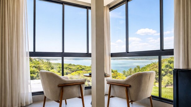 A room with large windows, two chairs, and a view of a landscape. - Pousada Casa Decore (Capitólio)