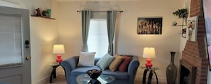 A living room with a sofa, two lamps, a painting, and a fireplace.