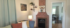A living room with a fireplace, a sofa, a lamp, and artwork on the wall.