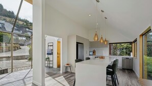 A modern kitchen with a large island, pendant lights, and a view of the outdoors. - Earnslaw Lakeview Retreat, close to town + parking (Queenstown)