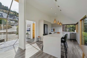 A modern kitchen with a large island, pendant lights, and a view of the outdoors. - Earnslaw Lakeview Retreat, close to town + parking (Queenstown)