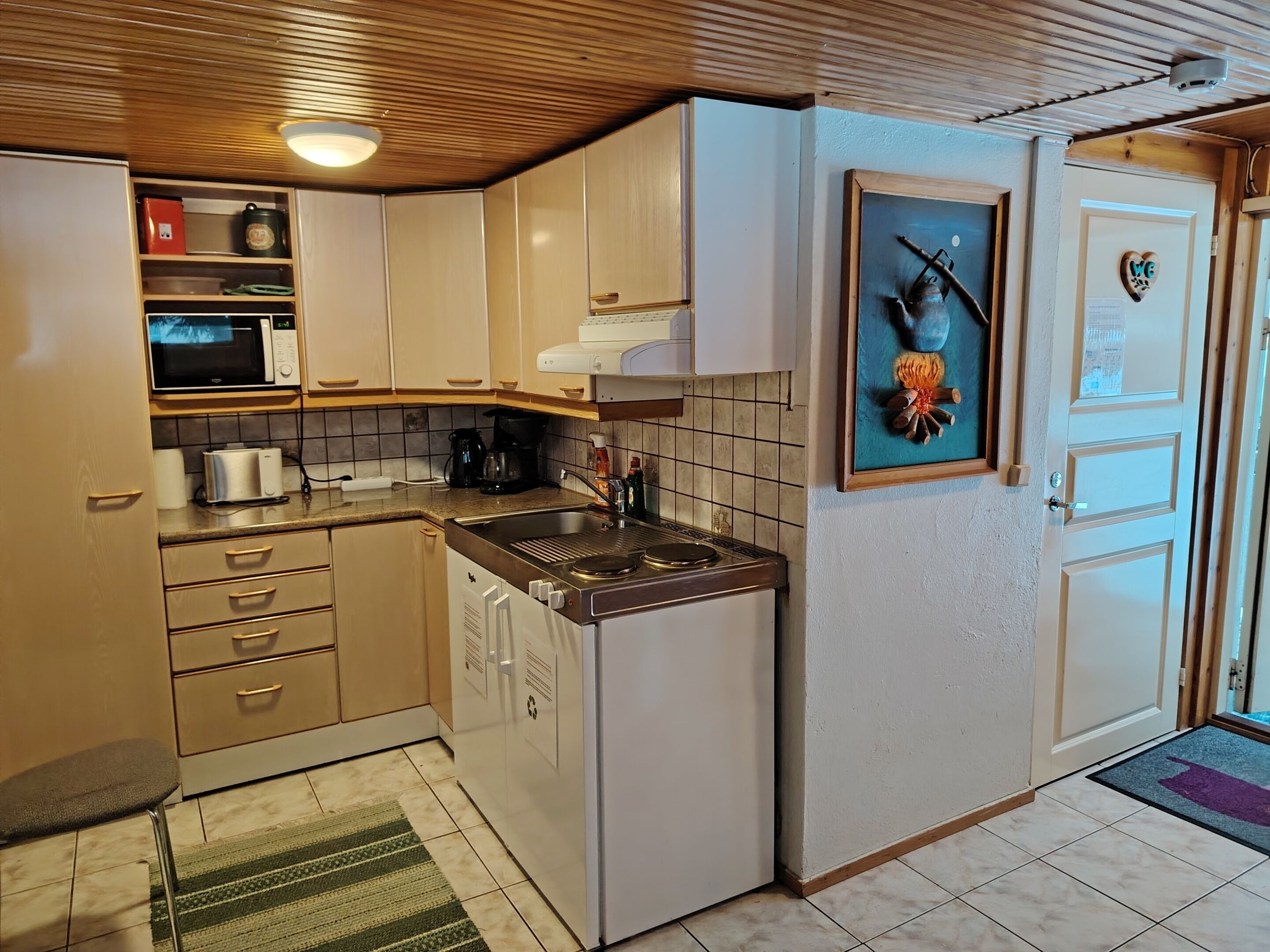 A compact kitchen with a microwave, coffee maker, and a sink.
