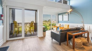 A spacious living area with a balcony, a sofa, a coffee table, and a view of the outdoors. - Rockaway Beach Oceanfront Views! Private Balcony, Beachfront Paradise! (Rockaway Beach)