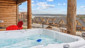 Un jacuzzi en una terraza de madera con vistas a edificios y colinas.