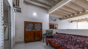 A room with a sofa, wooden cabinet, and a fan on the wall. - Casa  piscina a 180m da Praia Boraceia (Bertioga)