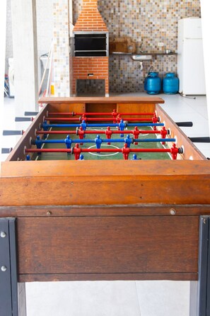 Ein Fußballtisch in einem Raum mit einer gefliesten Rückwand, einem Backofen und einem Kühlschrank.