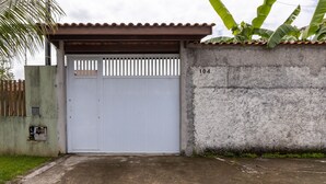 A gated entrance with a concrete wall, a metal roof, and a number '104' on the wall. - Casa  piscina a 180m da Praia Boraceia (Bertioga)