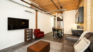 Un salon moderne avec un téléviseur à écran plat, un fauteuil rouge, un canapé marron et une table basse en bois.