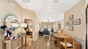 A spacious room with a wooden dining table, chairs, a large mirror, and a plush toy on a console table. - Epic Princess and Villains Hideaway-  Private Pool  Themed Rooms  Near Disney (Kissimmee)