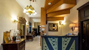 A reception area with a wooden reception desk, a chandelier, and a mirror on the wall. - HOTEL REGAL 1880 - Boutique Hotel Sinaia (Sinaia)