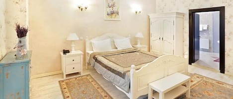 Un dormitorio con cama, mesitas de noche, un banco, un armario y un espejo.