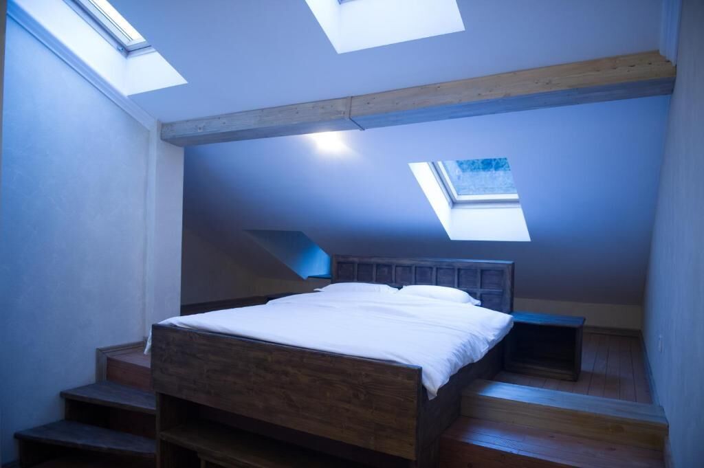 A bedroom with a skylight, wooden beams, and a bed.