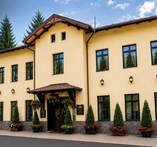 A two-story building with a yellow facade, multiple windows, and a covered entrance area with potted plants. - HOTEL REGAL 1880 - Boutique Hotel Sinaia (Sinaia)