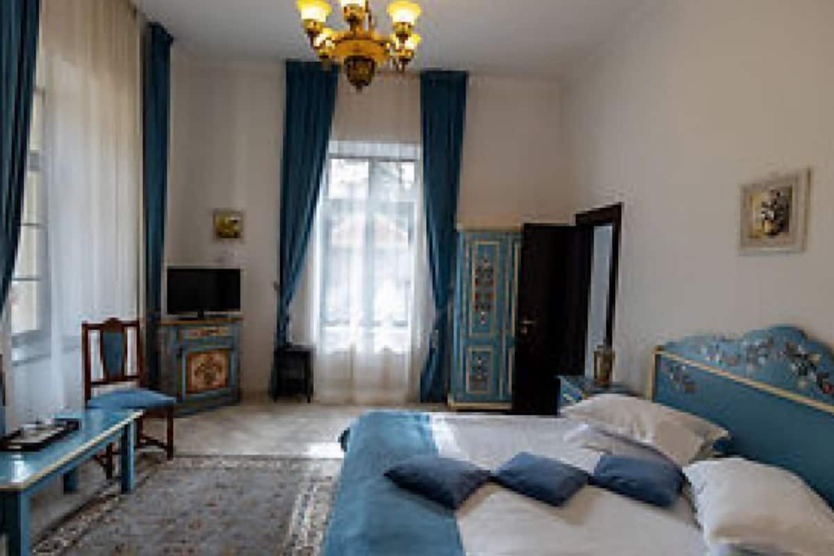 A bedroom with a bed, a TV, a desk, and a wardrobe.