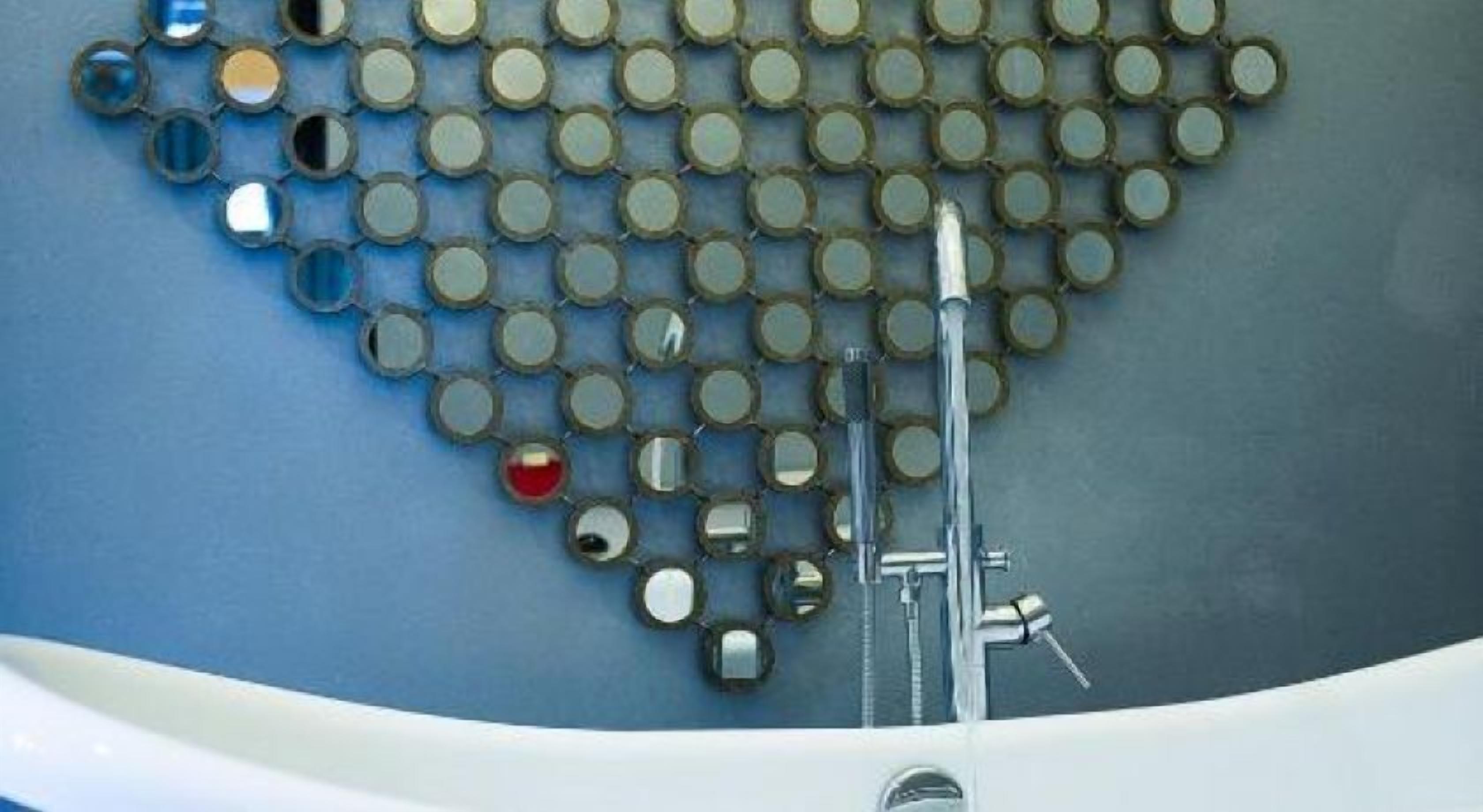 A bathroom with a blue wall, a white bathtub, and a mirror with circular frames.