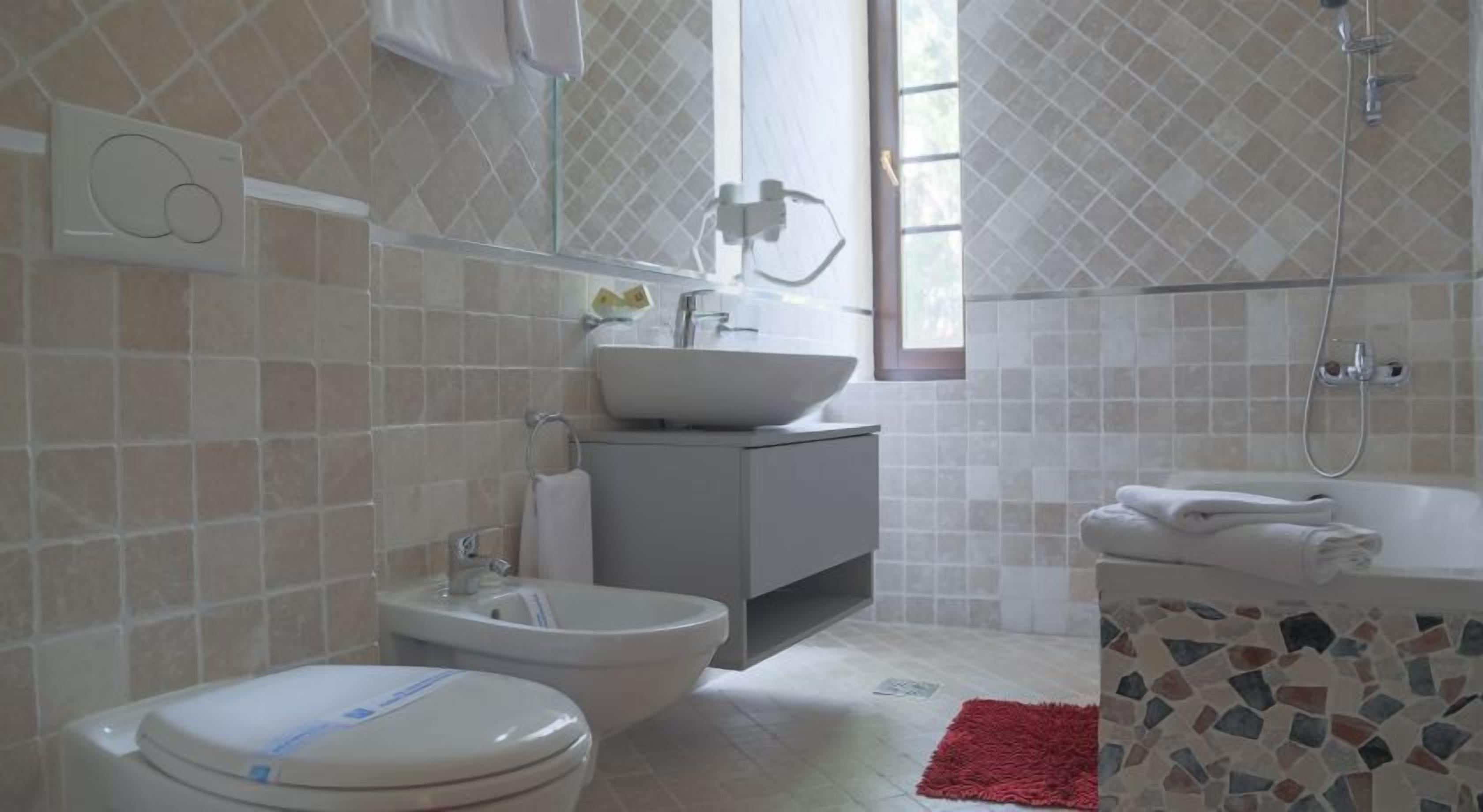 A bathroom with a toilet, bidet, sink, and shower.