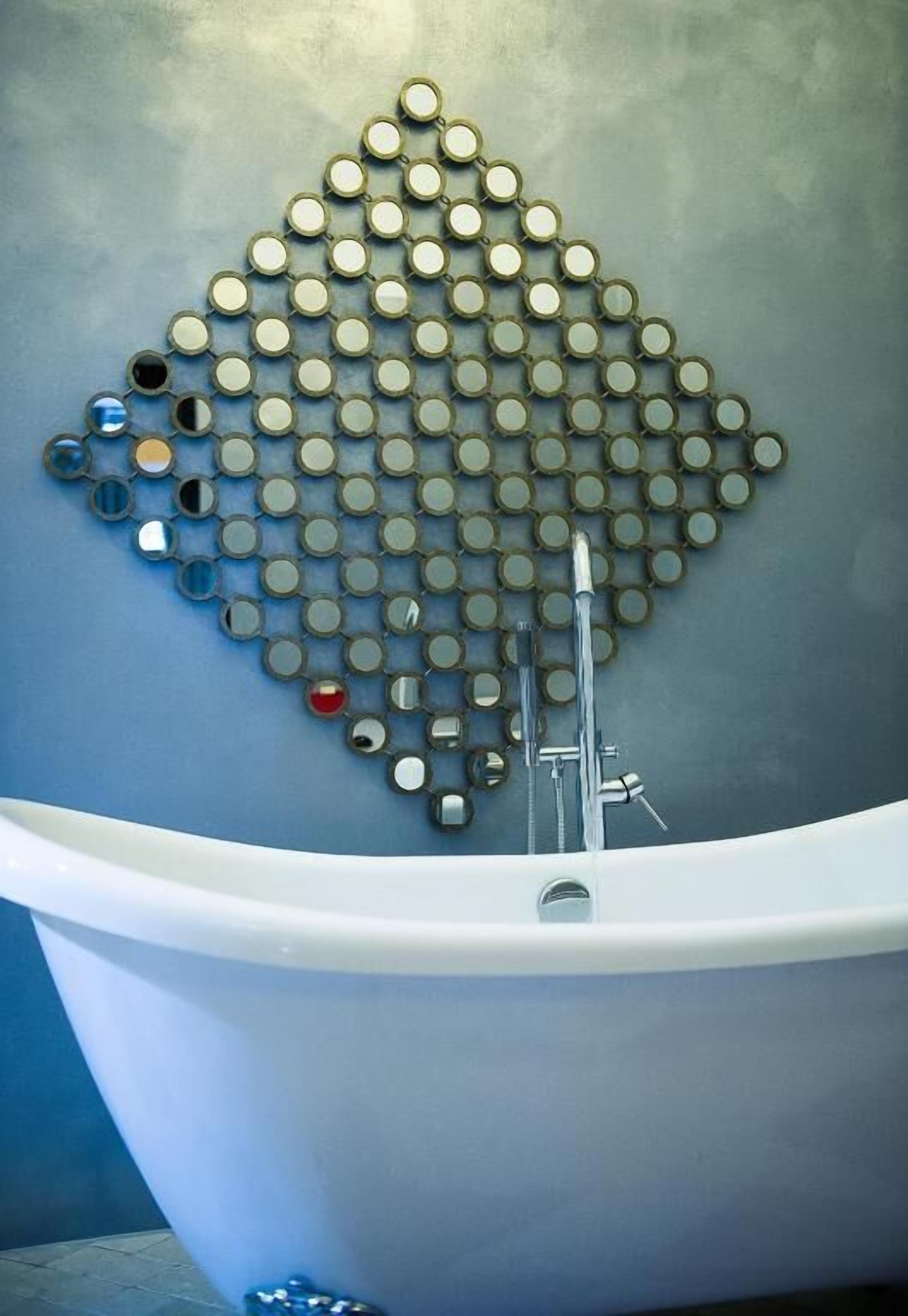 Una bañera con un diseño único de mosaico circular en la pared.