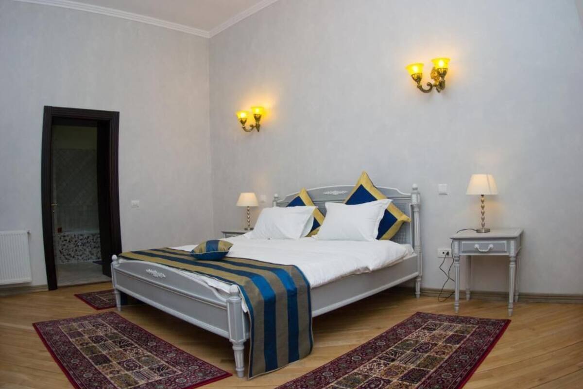 A bedroom with a bed, two bedside tables, a door, and two wall-mounted light fixtures.