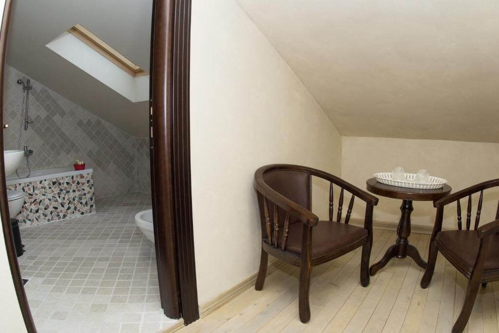Quarto com claraboia, banheiro com parede em mosaico e área de jantar com mesa e cadeiras.