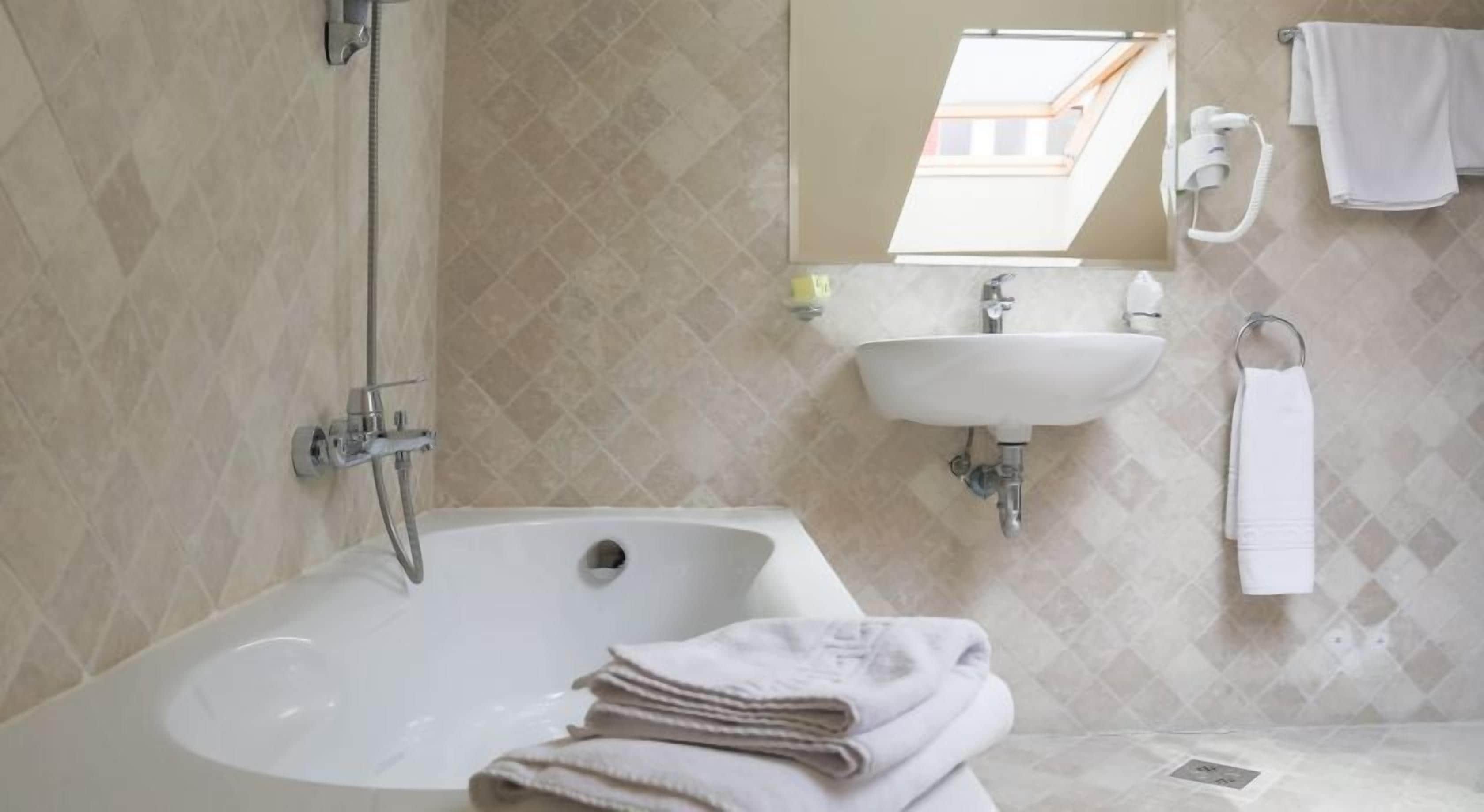A bathroom with a bathtub, a sink, and a mirror.