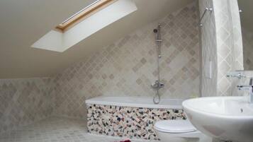 A bathroom with a skylight, a shower, a toilet, and a sink.
