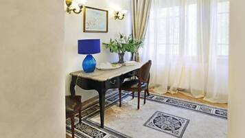 Un comedor con una mesa, sillas, una lámpara, una planta y un tapete estampado.