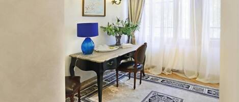 Un comedor con una mesa, sillas, una lámpara, una planta y un tapete estampado.