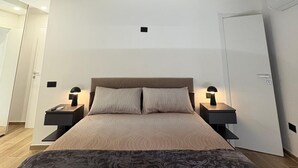 Ein Schlafzimmer mit einem großen Bett, zwei Nachttischen, einer Deckenleuchte und einer Tür.