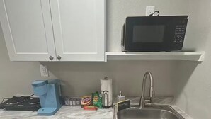 A compact kitchen with a microwave, a sink, and cabinets.
