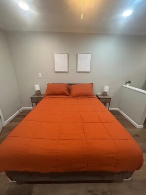 A bedroom with a large bed, two bedside tables, and a nightstand. - The Orange Sunset (Cleveland)