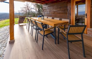 An outdoor wooden deck with a long table and chairs, a hanging light fixture, and a view of the landscape. - Amazing home in Veliko Trgovisce with sauna (Veliko Trgovisce)