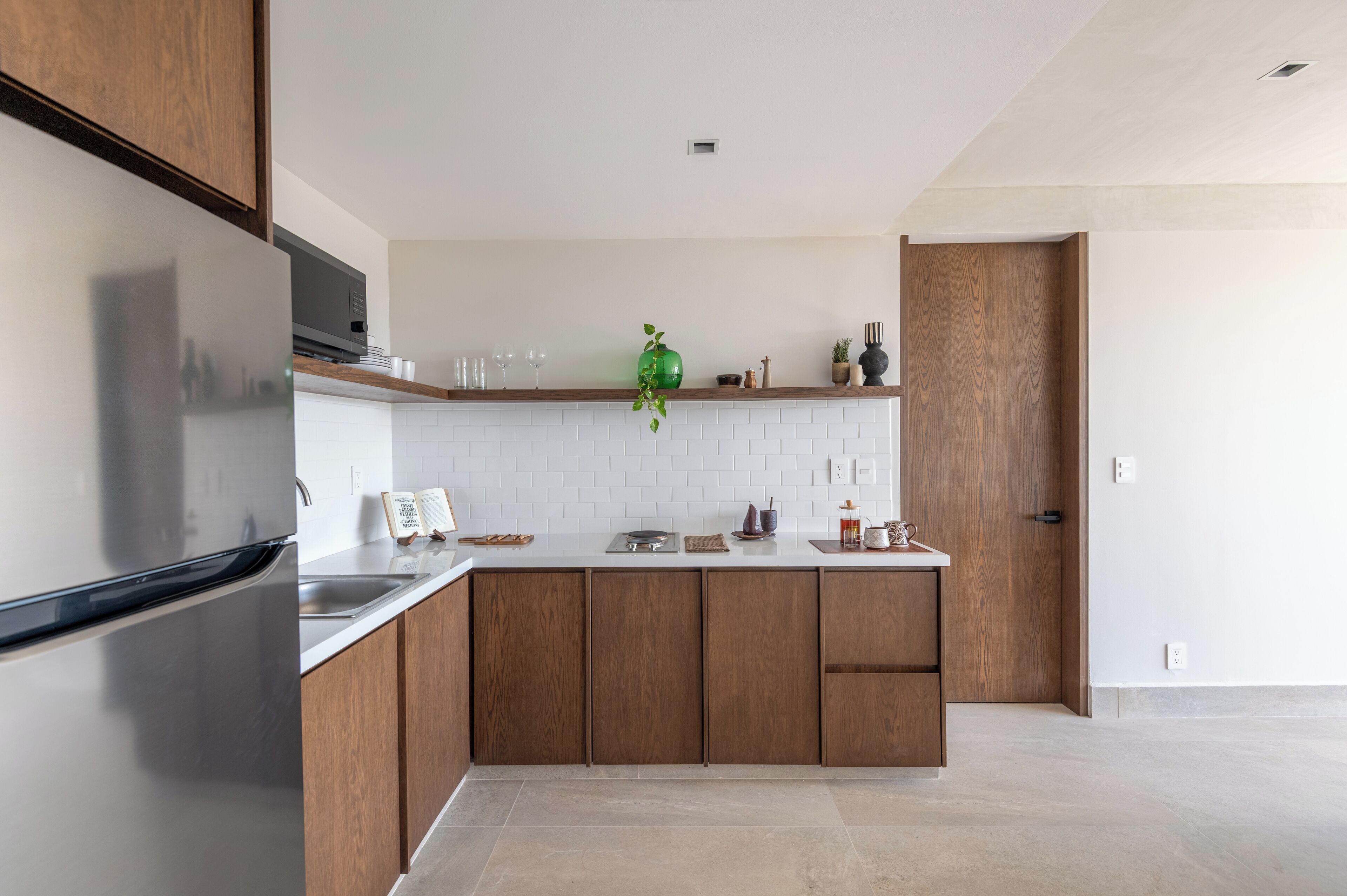 Uma cozinha moderna com armários de madeira, uma geladeira de aço inoxidável e um backsplash de azulejos brancos.