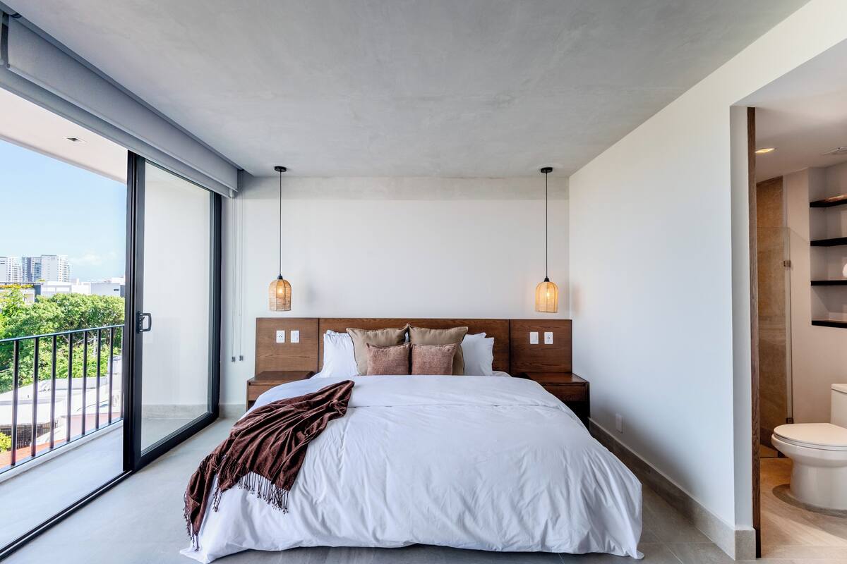 Une chambre moderne avec un grand lit, un balcon et une vue sur la ville.