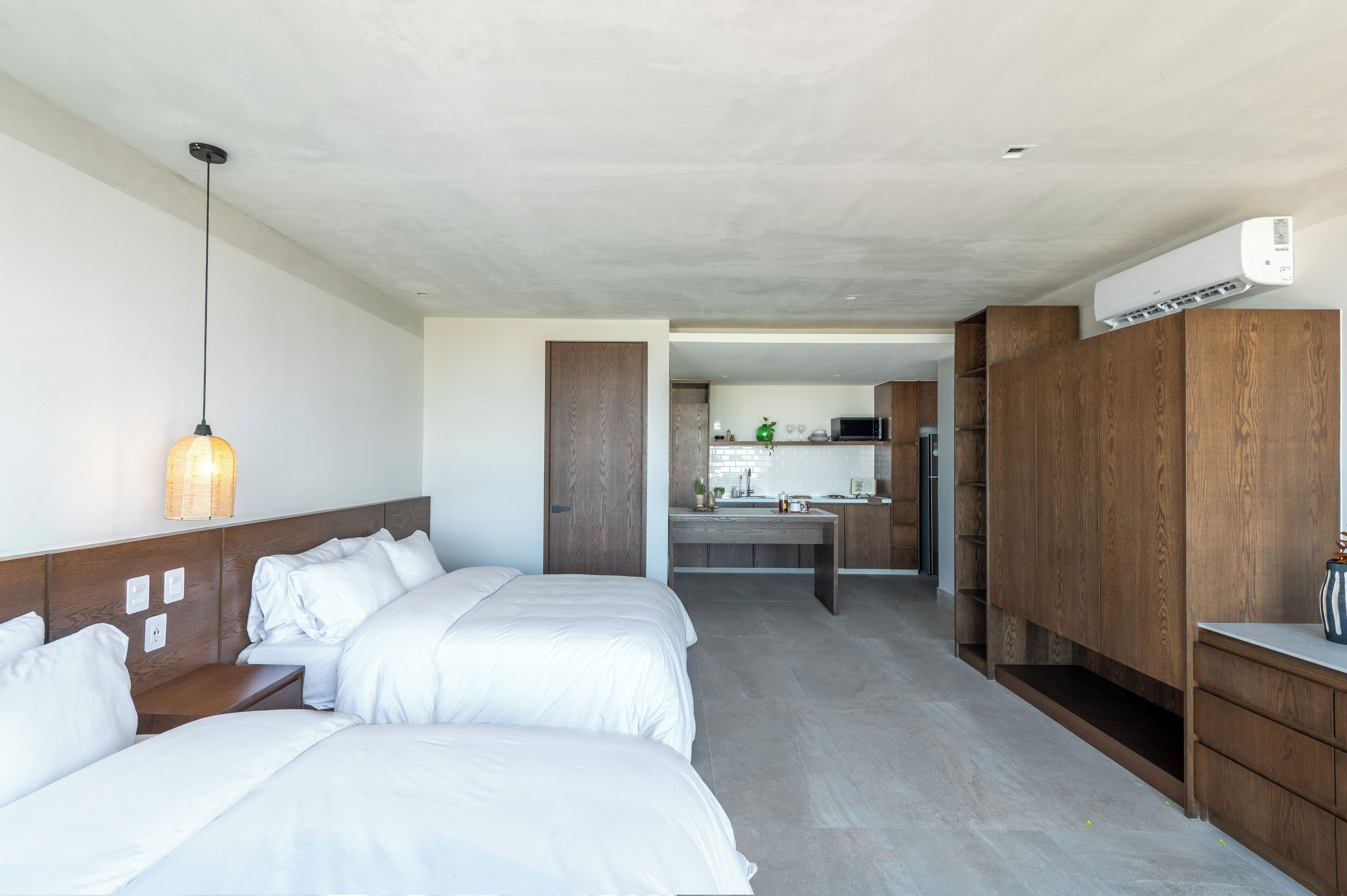 Une chambre d’hôtel avec deux lits, une kitchenette et une armoire en bois.