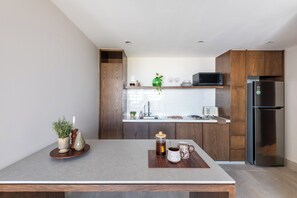 Eine moderne Küche mit Holzschränken, einem Edelstahlkühlschrank und einer Arbeitsplatte mit Kaffeemaschine und Tasse.