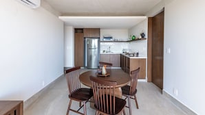 A modern kitchen with a central island, wooden chairs, and a dining table.