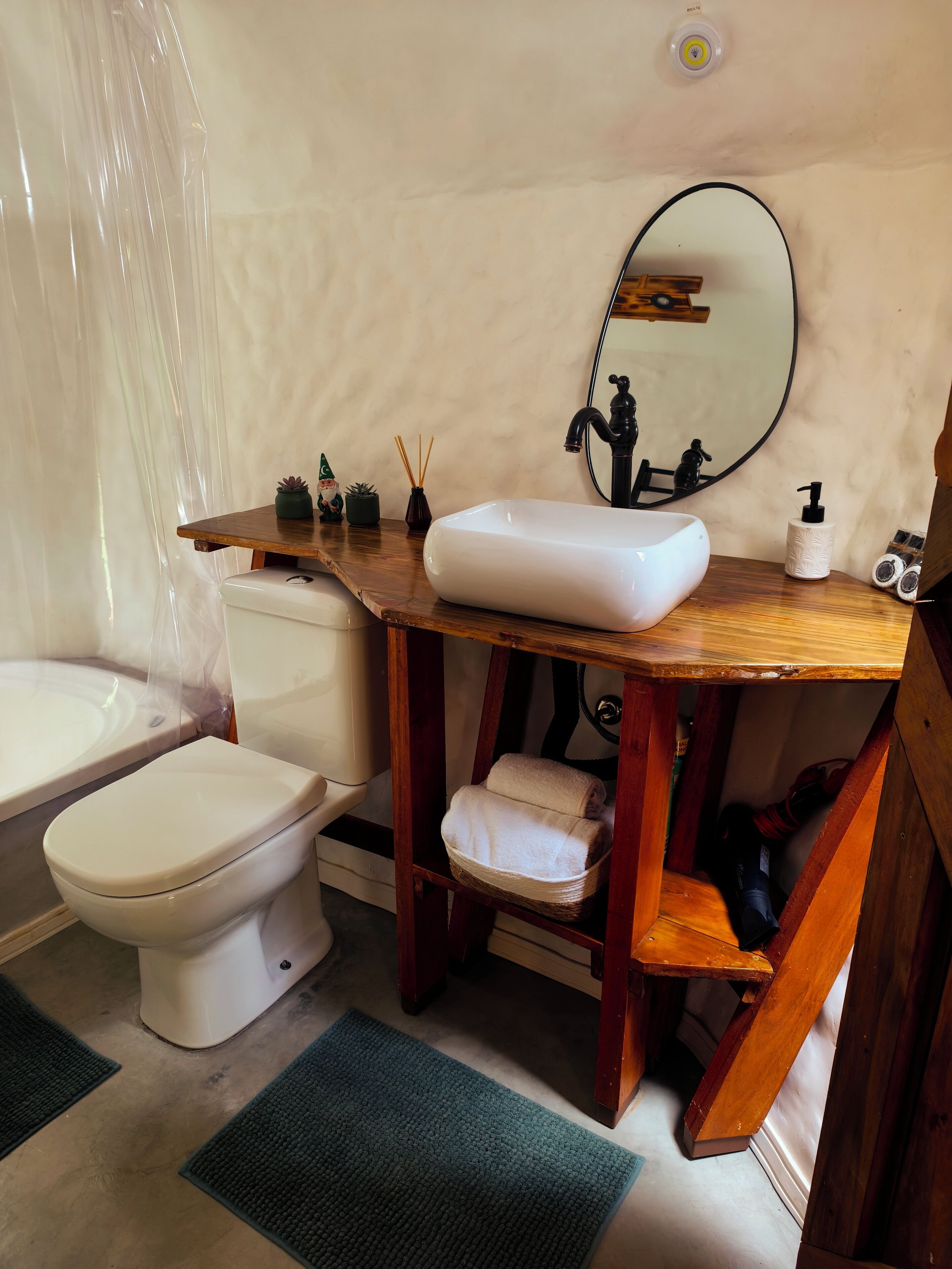 Une salle de bain avec un meuble-lavabo en bois, un lavabo blanc, un miroir, des toilettes et une baignoire.