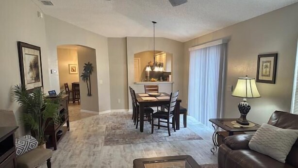 A living room with a brown leather sofa, a coffee table, and a dining area with a table and chairs. - The Villages 2 bedroom / 2 bath home minutes from Lake Sumter Landing (The Villages)