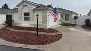 A single-story house with a garage, a driveway, and a landscaped area with mulch. - The Villages 2 bedroom / 2 bath home minutes from Lake Sumter Landing (The Villages)