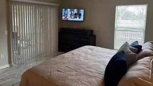 A bedroom with a bed, a television mounted on the wall, a ceiling fan, and a window with blinds. - The Villages 2 bedroom / 2 bath home minutes from Lake Sumter Landing (The Villages)
