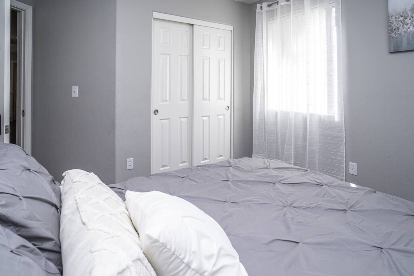 A bedroom with a bed, a wardrobe, and a window with curtains.